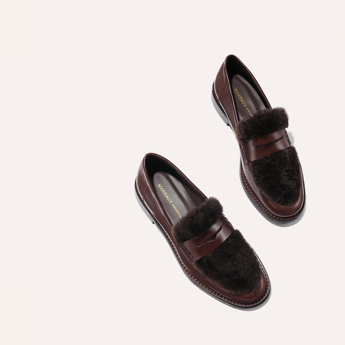 The Marlowe Loafer by Margaux in Mahogany Calf and Shearling, featuring brown leather with dark fur accents, displayed against a light neutral background.