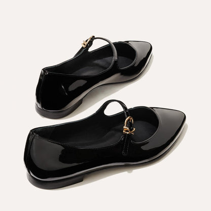 The Mary Jane in Black Patent, a ballet flat with a pointed toe and an adjustable strap for a secure fit.