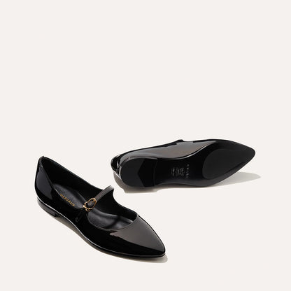 The Mary Jane in Black Patent, a ballet flat with a pointed toe and an adjustable strap for a secure fit.
