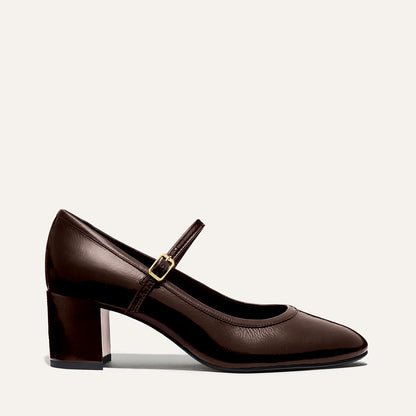 The Mira Jane - Cocoa Crinkle Patent by margaux-development is a dark brown Mary Jane shoe with a round toe, low block heel, and an adjustable gold-buckle strap, shown on a plain light background.
