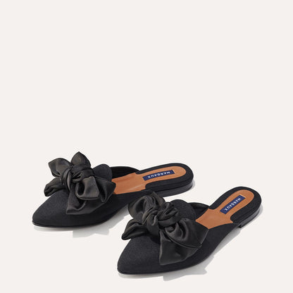The Mule in Black Grosgrain, a slip-on silhouette featuring a pointed toe and oversized bow detail. 