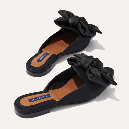 The Mule in Black Grosgrain, a slip-on silhouette featuring a pointed toe and oversized bow detail. 