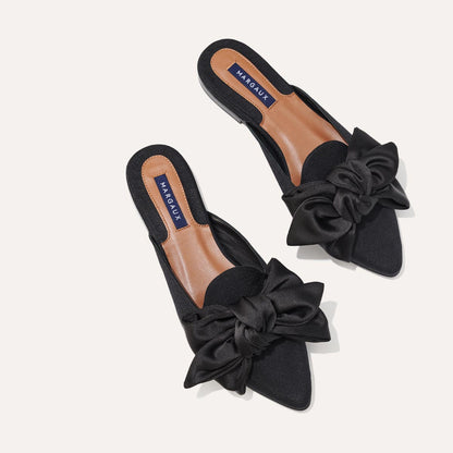 The Mule in Black Grosgrain, a slip-on silhouette featuring a pointed toe and oversized bow detail. 