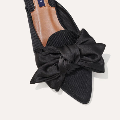 The Mule in Black Grosgrain, a slip-on silhouette featuring a pointed toe and oversized bow detail. 