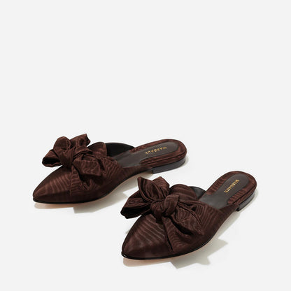 The Mule in Espresso Moire, a slip-on silhouette featuring a pointed toe and oversized bow detail. 