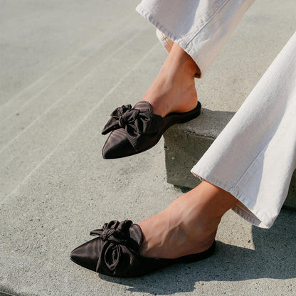 The Mule in Espresso Moire, a slip-on silhouette featuring a pointed toe and oversized bow detail. 