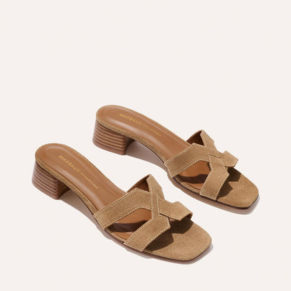 The MX 35 - Biscotti Suede by Margaux: tan suede open-toe slide sandals featuring crisscross straps and low stacked heels, shown on a neutral background.
