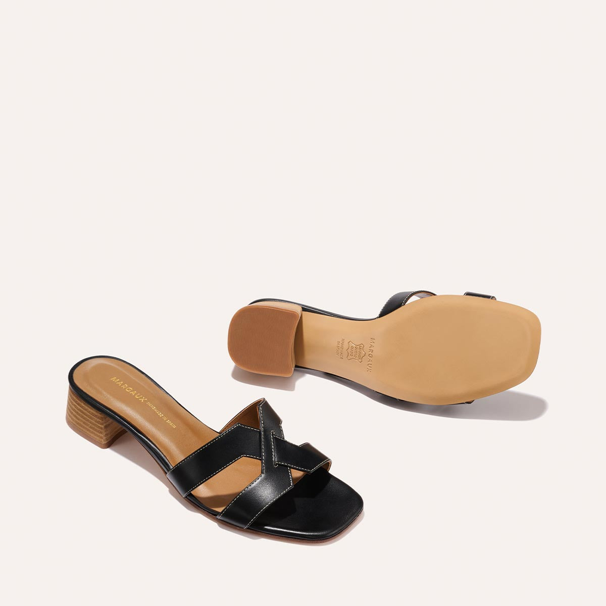 The MX 35 - Black Calf by Margaux-development: black open-toe slip-ons featuring crisscross leather straps and low block heels, shown from the side and sole views against a light background.