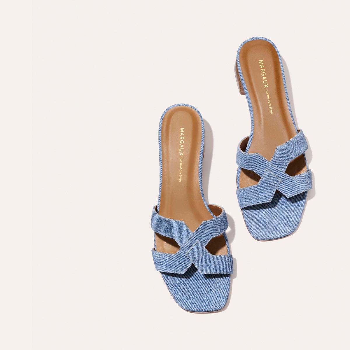 The MX 35 - Denim Suede by Margaux-development: blue denim sandals with crisscross straps, tan insoles, open toe, and flat sole are shown on a light background.