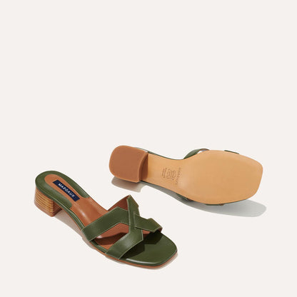 The MX 35 - Olive Calf by margaux-development: green heeled sandals with crisscross straps, tan insoles, brown block heels, and tan outsoles—an elevated update on a classic style, shown from side and sole views on white background.