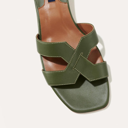 Close-up of The MX 35 - Olive Calf by margaux-development: a green leather sandal with wide crisscross straps, white stitching, open toe, tan insole, and an elevated block heel for a modern look.