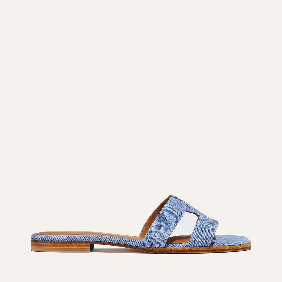 The MX Sandal - Denim Suede by Margaux: a single light blue denim suede flat slide sandal with an open toe and wide cutout strap, shown in side profile against a plain light background.