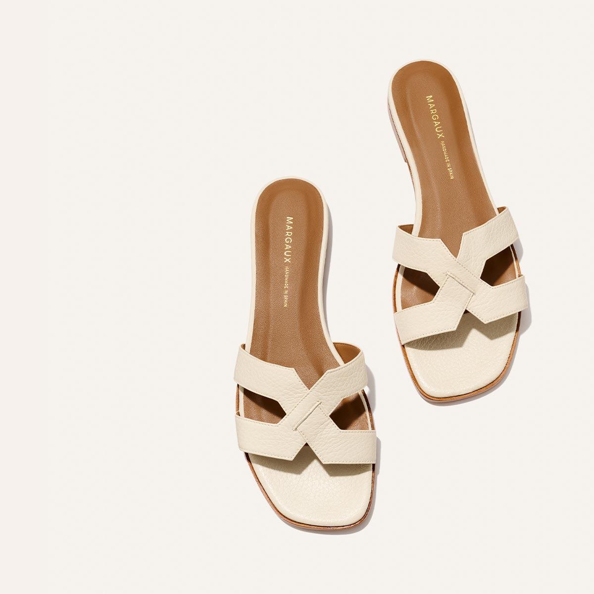 The Margaux MX Sandal in Ecru Tumbled Nappa features luxe cream crisscross leather straps and tan soles—perfect for effortless everyday style—shown on a white background.