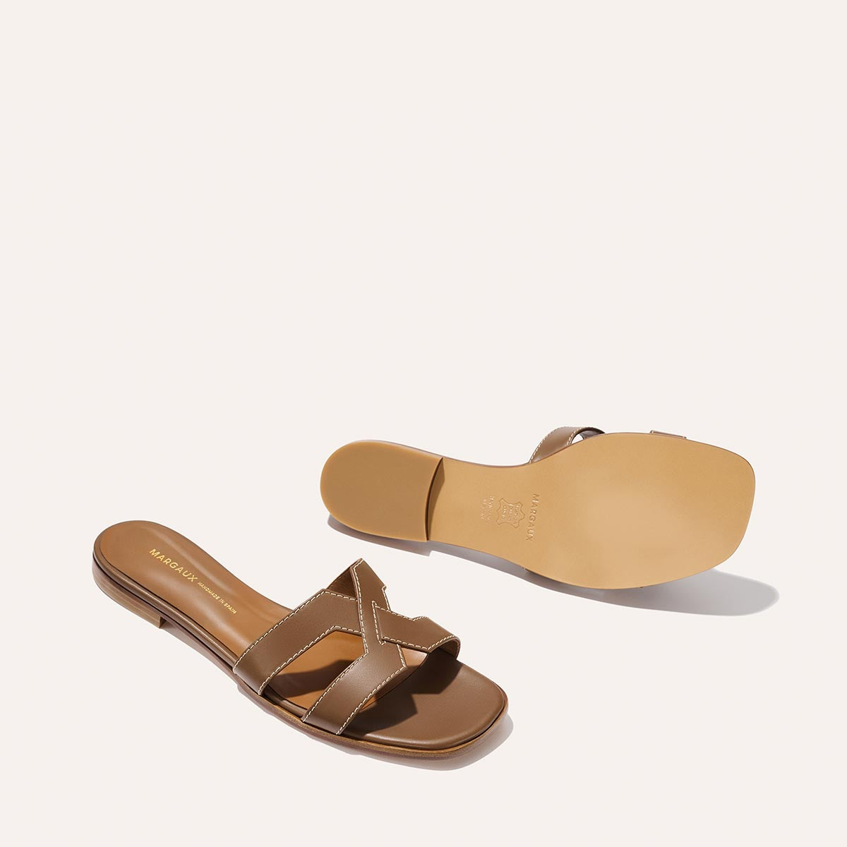 The MX Sandal - Mocha Calf by Margaux, featuring brown crisscross straps, is shown with one sandal top view and the other bottom view, both displayed on a light background.
