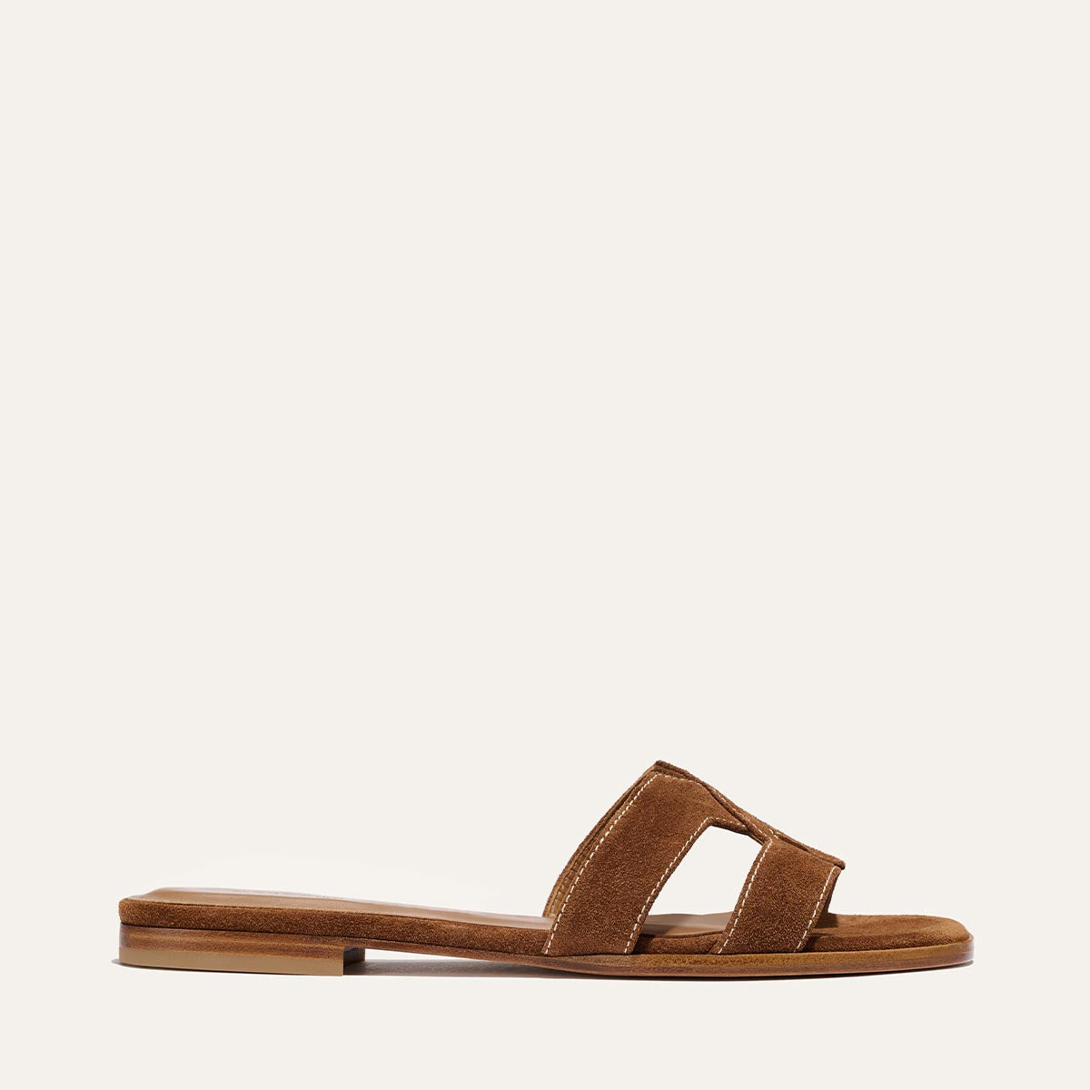 The MX Sandal in Saddle Suede by Margaux features open-toe brown suede, wide cut-out straps, and a low heel—perfect for everyday wear. Shown on a plain light background.