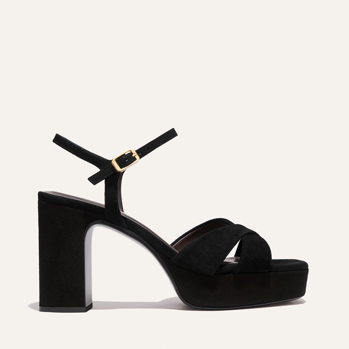 The Paloma Platform by Margaux in black suede features crisscross front straps, a padded platform, thick block heel, and adjustable gold-buckle ankle strap for all-night comfort, shown against a plain white background.