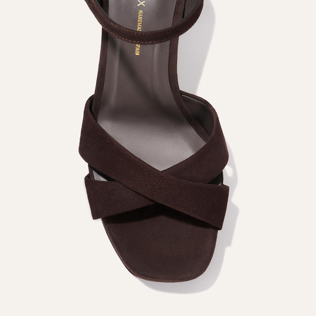 Top view of Margaux’s The Paloma Platform - Espresso Suede: a dark brown suede heeled sandal with square toe, two wide crisscrossing straps, sleek minimalist design, and padded platform for comfort, shown on a light background.