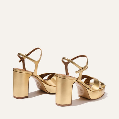 The Paloma Platform - Gold Nappa by Margaux is shown on a light background, highlighting its comfortable straps, block heels, and padded platform in both back and side views.