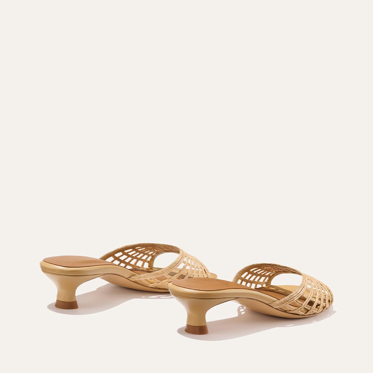 Pair of beige woven high-heeled shoes on a white background