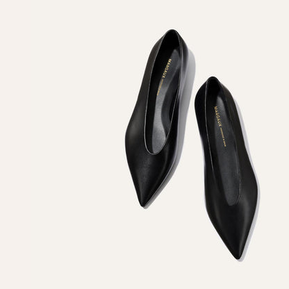 The Parra - Black Nappa flats by margaux-development feature a minimalist pointed-toe leather design with gold branding on the insoles, displayed against a light background.