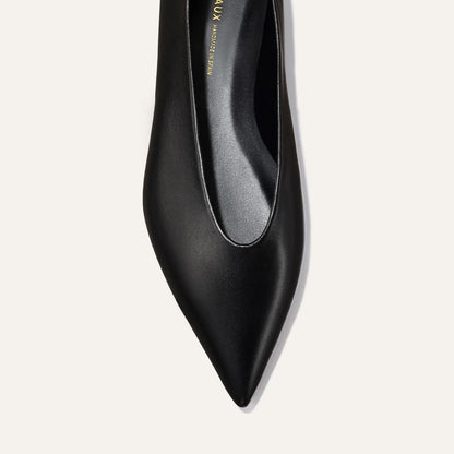 A close-up, top view of The Parra - Black Nappa pointed-toe high heel by margaux-development on a light background.