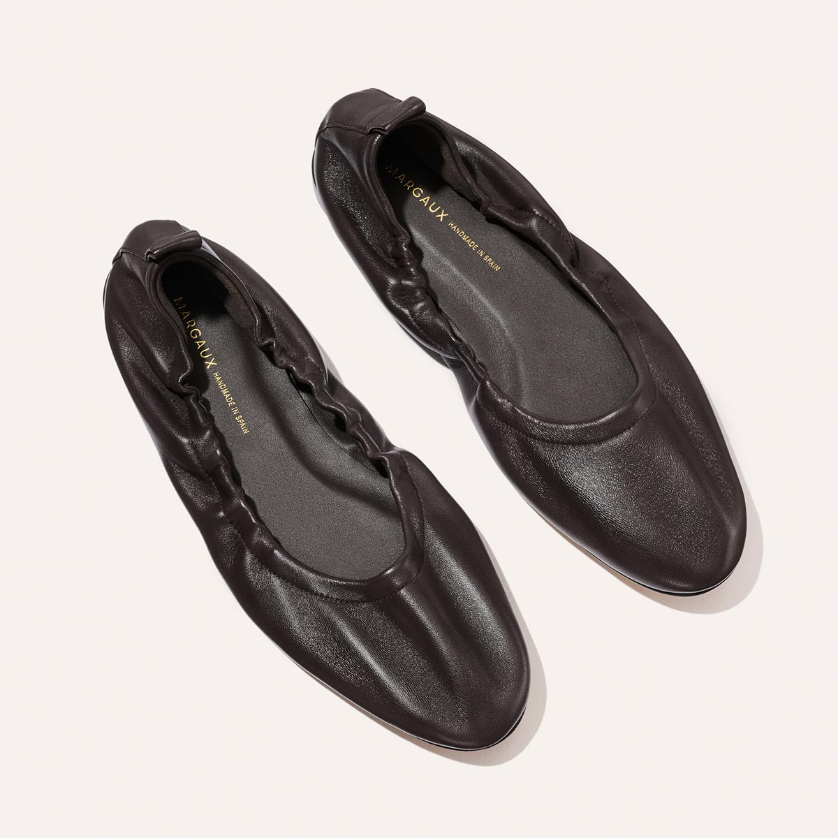 The Pascale - Espresso Nappa by Margaux, a pair of dark brown supple leather ballet flats featuring ruched detailing, elasticated backs, and rounded toes, displayed on a light background.