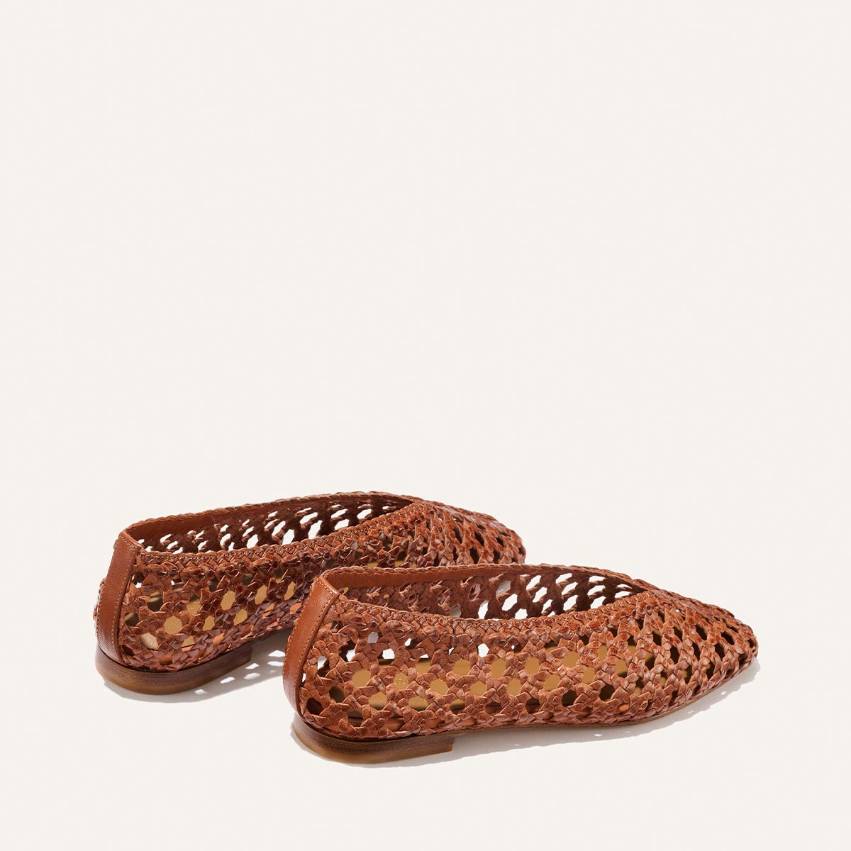 The Margaux Woven Paz in Saddle Leather features luxuriously soft, handwoven leather with a lattice-style open-weave design, closed toes, and low heels. Shown against a plain white background.