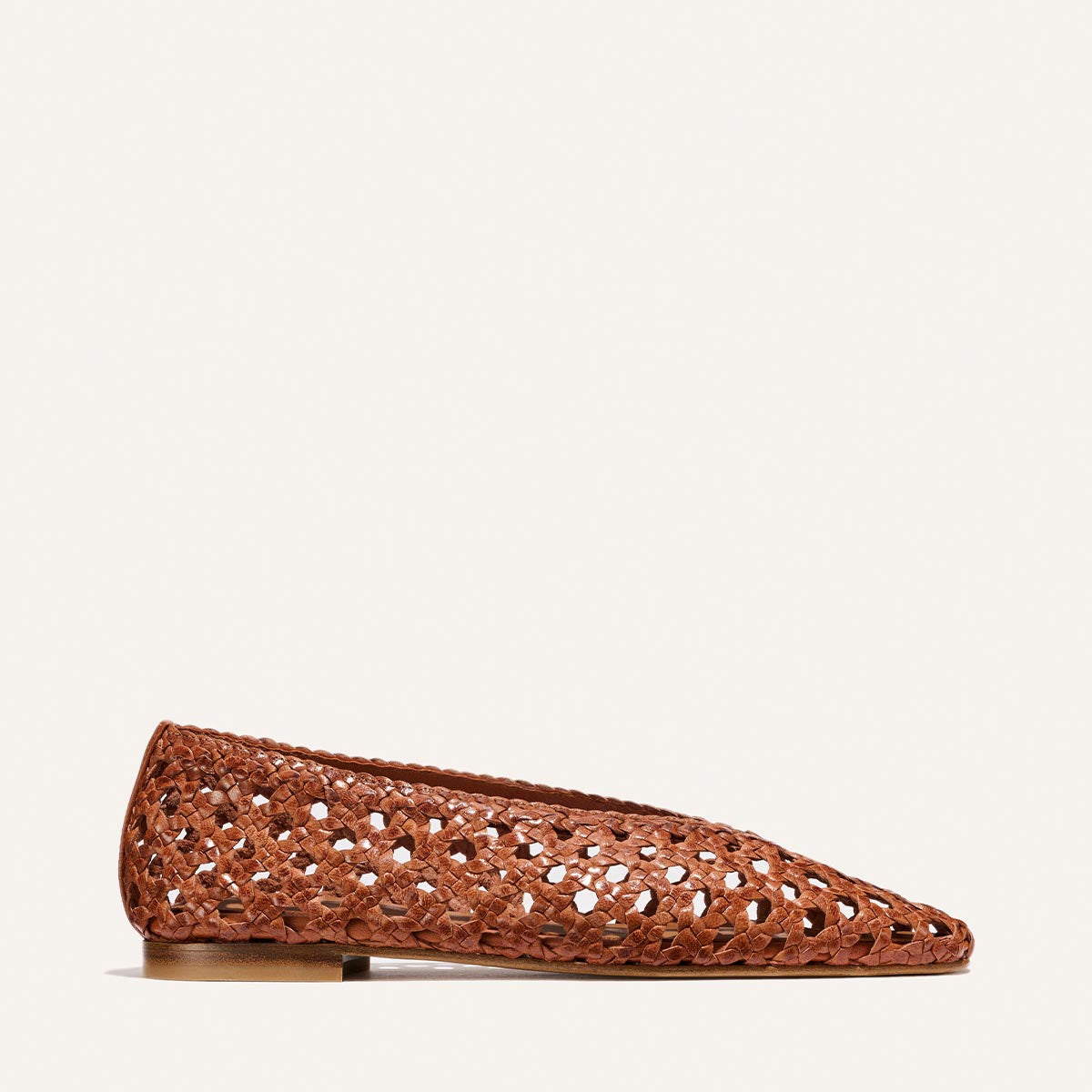 The Margaux Woven Paz - Saddle Leather is a brown handwoven flat with a pointed toe, intricate open-weave design, and low heel, shown on a plain light background.