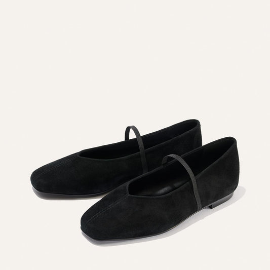 A pair of Margaux “The Phoebe” black suede ballet flats featuring a single thin strap across the top, displayed on a plain off-white background.