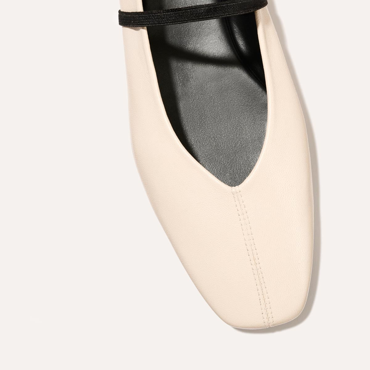 The Phoebe in smooth Bone Nappa leather, a ballet flat with a squared off toe, high vamp and elastic Mary Jane strap.