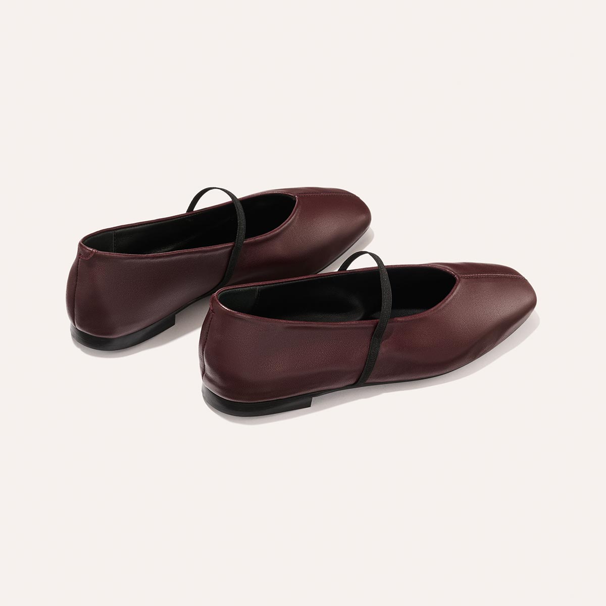 The Phoebe - Burgundy Nappa by margaux-development: burgundy ballet flats with black elastic straps, sacchetto construction for flexible comfort, rounded toe, and flat heel, shown on a plain light background.