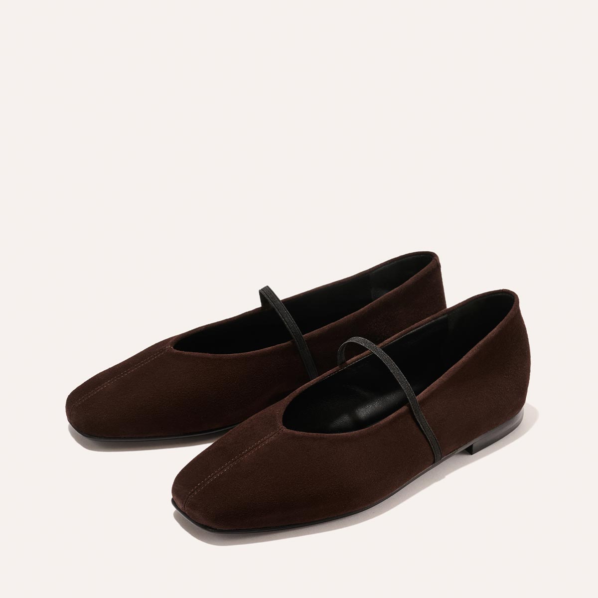 The Phoebe - Espresso Suede by margaux-development: brown suede ballet flats with black soles and a thin black strap, expertly crafted with sacchetto construction for exceptional comfort, shown on a light background.