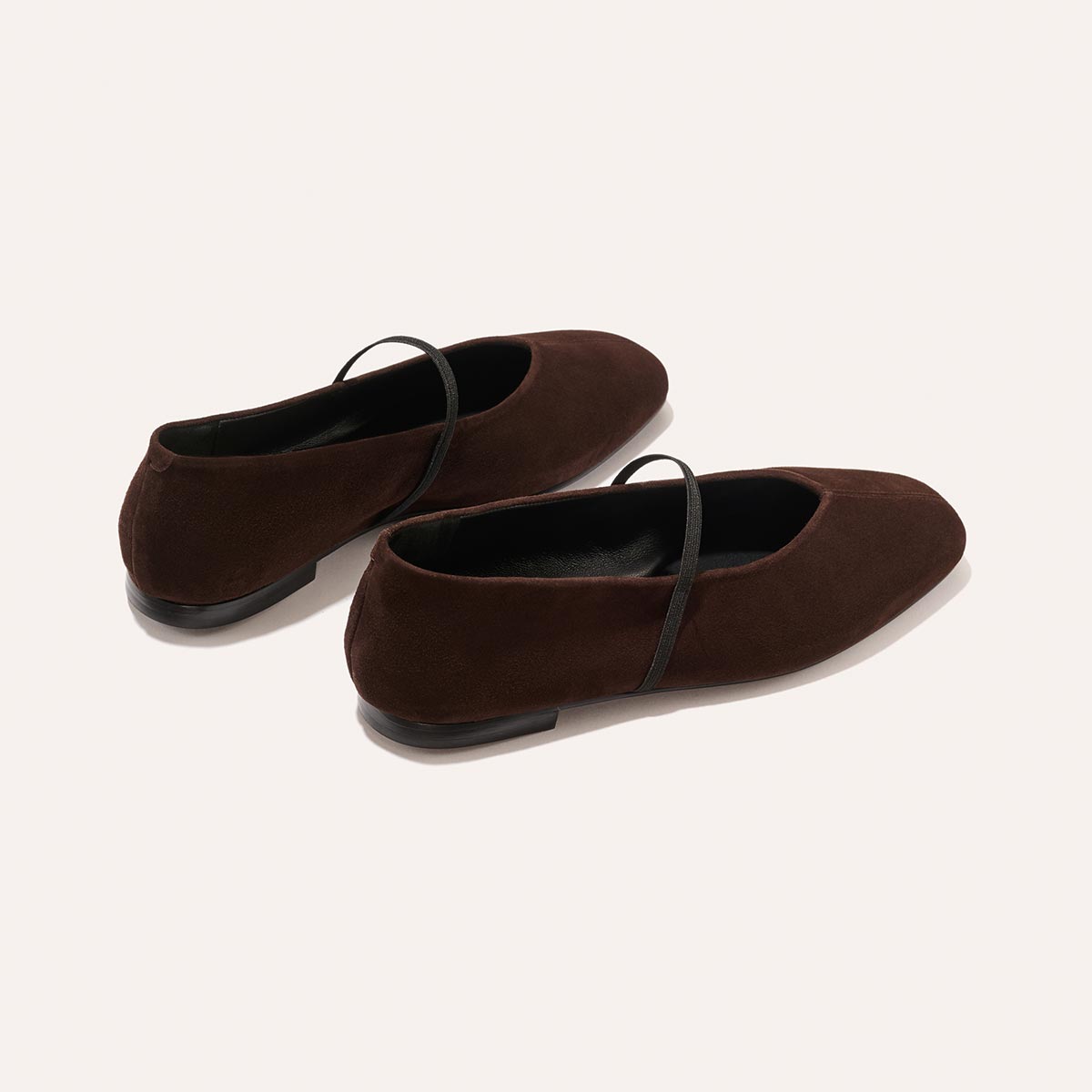 The Phoebe - Espresso Suede by margaux-development are dark brown suede Mary Jane flats featuring thin black straps, black soles, a square toe, and sacchetto construction for extra comfort, shown against a light background.