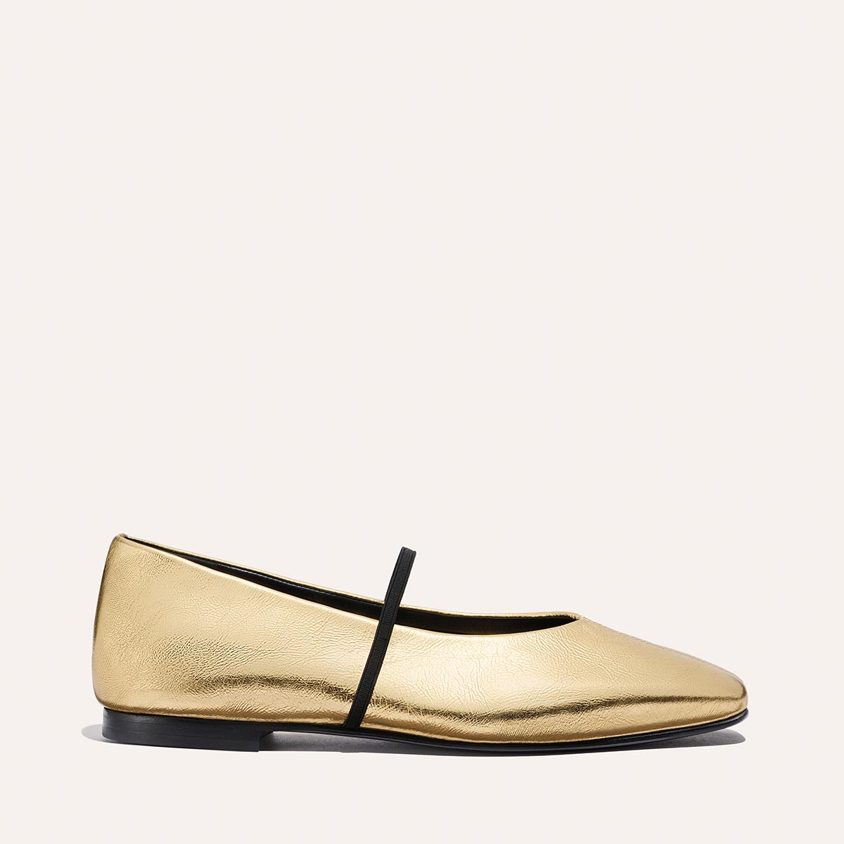 The Phoebe - Gold Crinkle Nappa by margaux-development is a single gold deconstructed flat with a rounded toe, black sole, and a thin black elastic strap across the top, displayed on a neutral background.