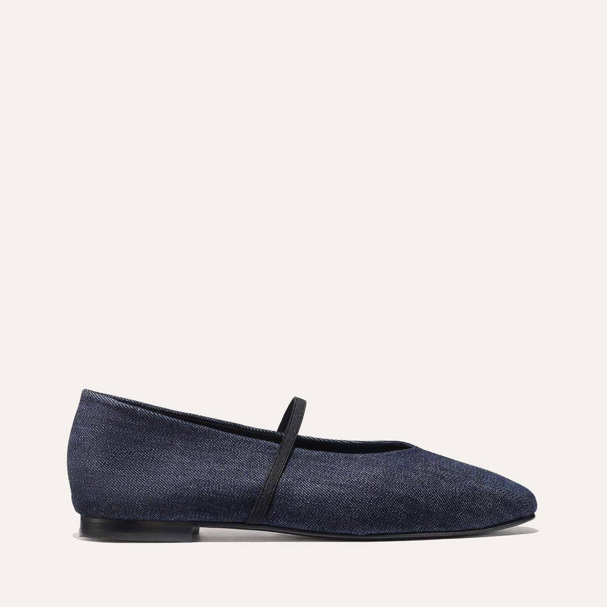 The Phoebe - Indigo Denim by margaux-development is a single deconstructed flat in dark blue denim with a thin black strap across the top, displayed in profile against a plain light background.