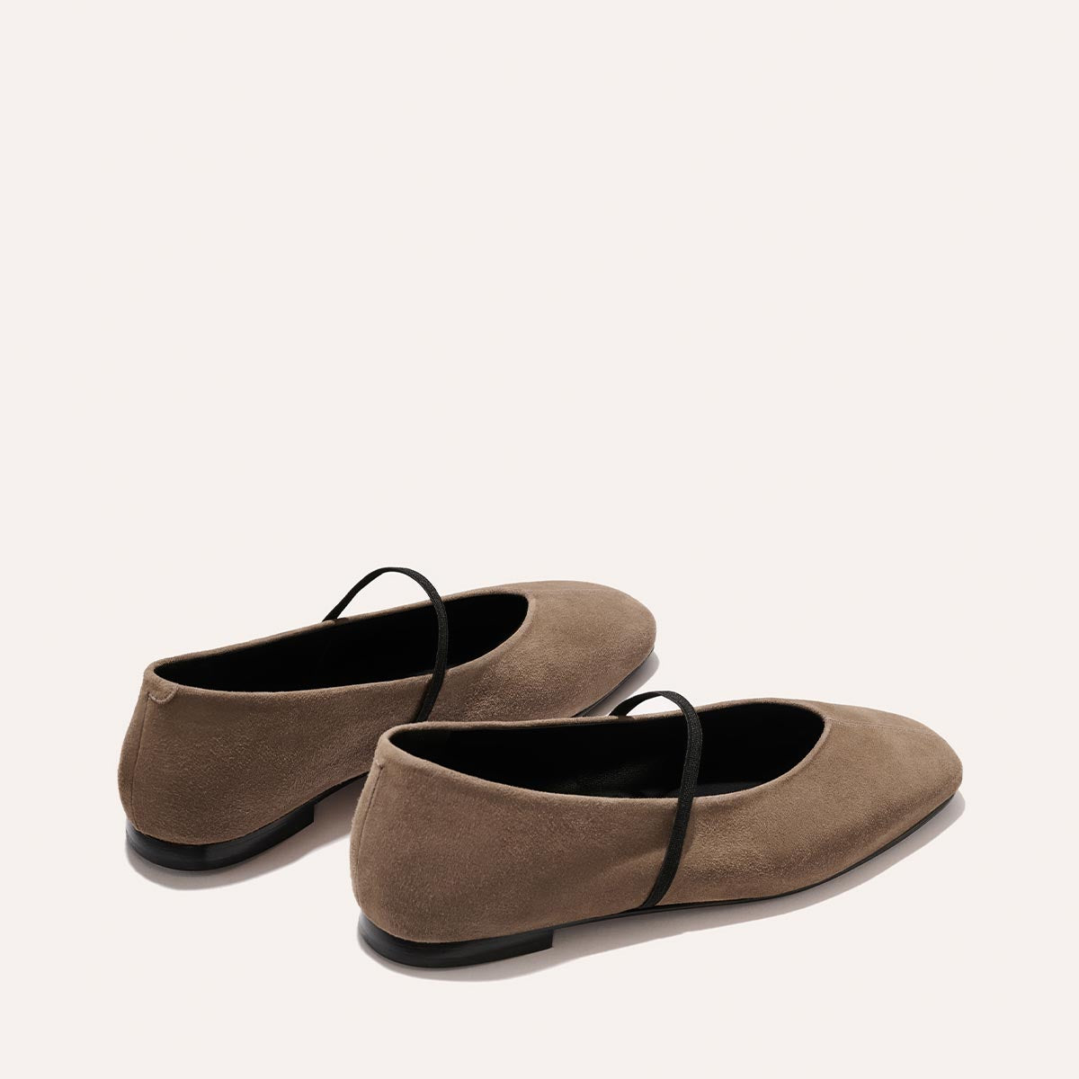 The Phoebe - Mushroom Suede by Margaux: taupe suede ballet flats with black soles and a slim black strap, shown on an off-white background.