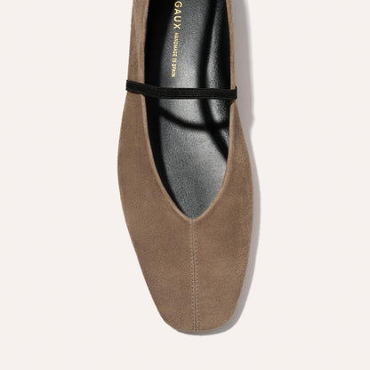A close-up top view of Margaux's The Phoebe - Mushroom Suede ballet flat shows its pointed toe and thin black elastic strap, displayed on a light background.
