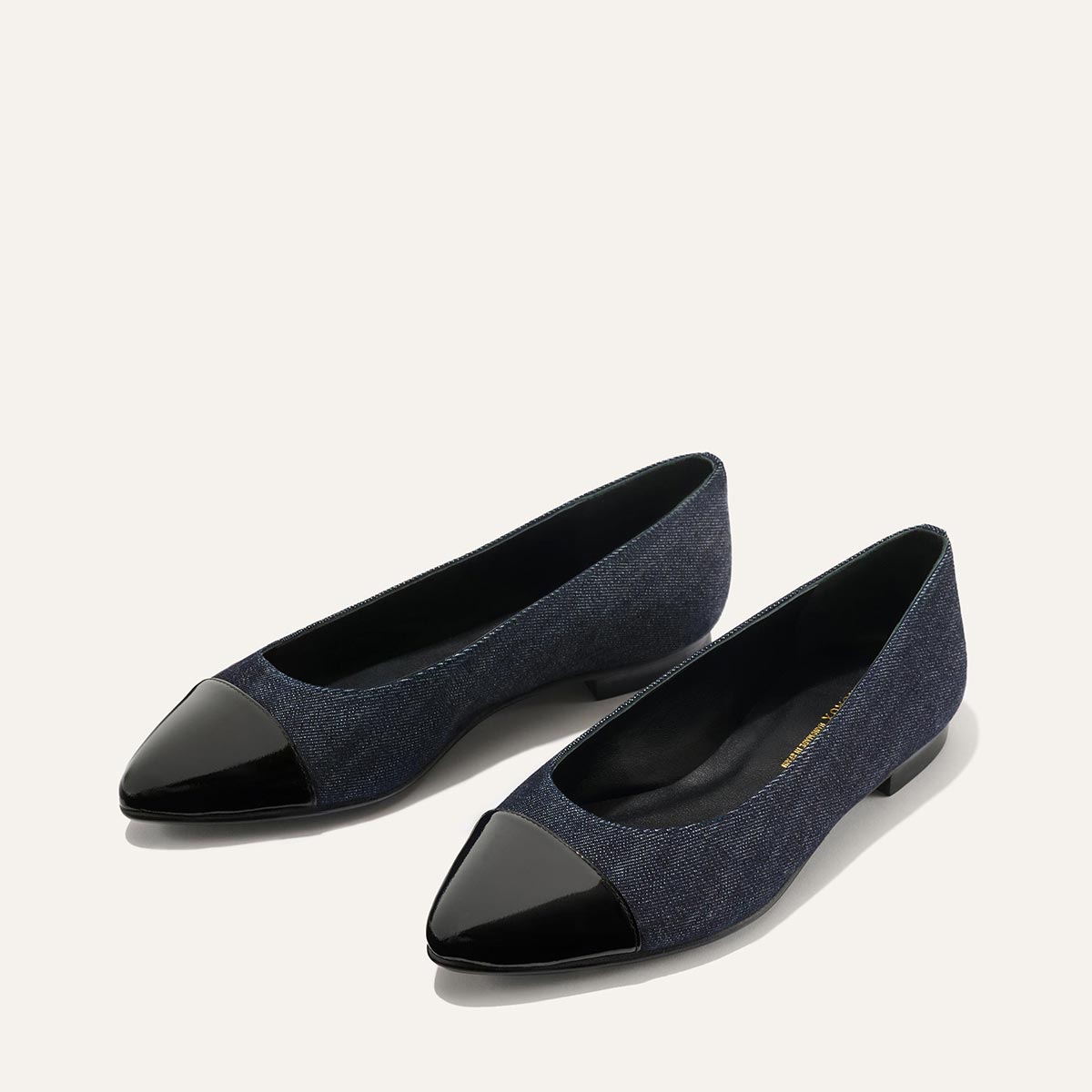 The Pointe - Indigo Denim and Patent by margaux-development showcases sleek womens flats in indigo denim with shiny black patent pointed toe caps, set against a light background.