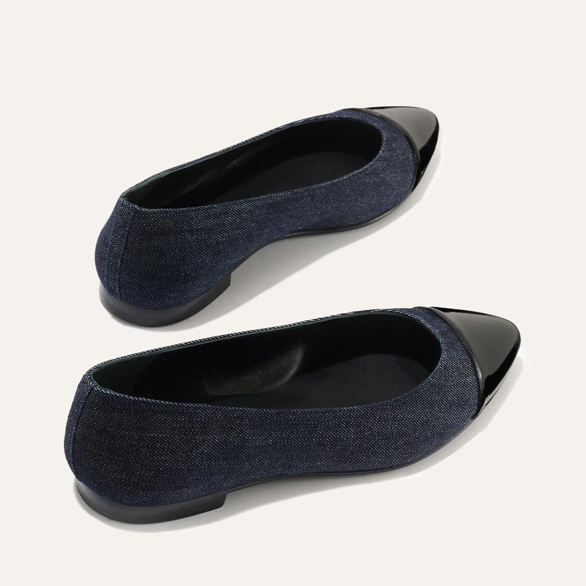 The Pointe - Indigo Denim and Patent by margaux-development features navy ballet flats with black shiny patent leather cap toes, a sleek silhouette, classic rounded edges, and flat soles.