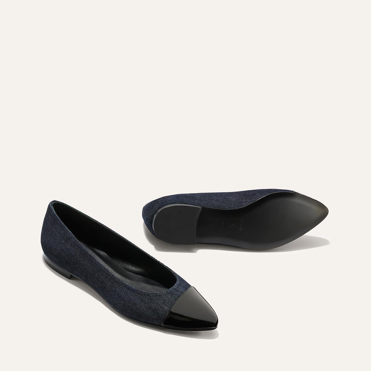 The Pointe - Indigo Denim and Patent by margaux-development: dark blue flats with a sleek silhouette and black patent leather pointed toe caps. One shoe stands upright, the other lies on its side, displaying the sole against a light background.