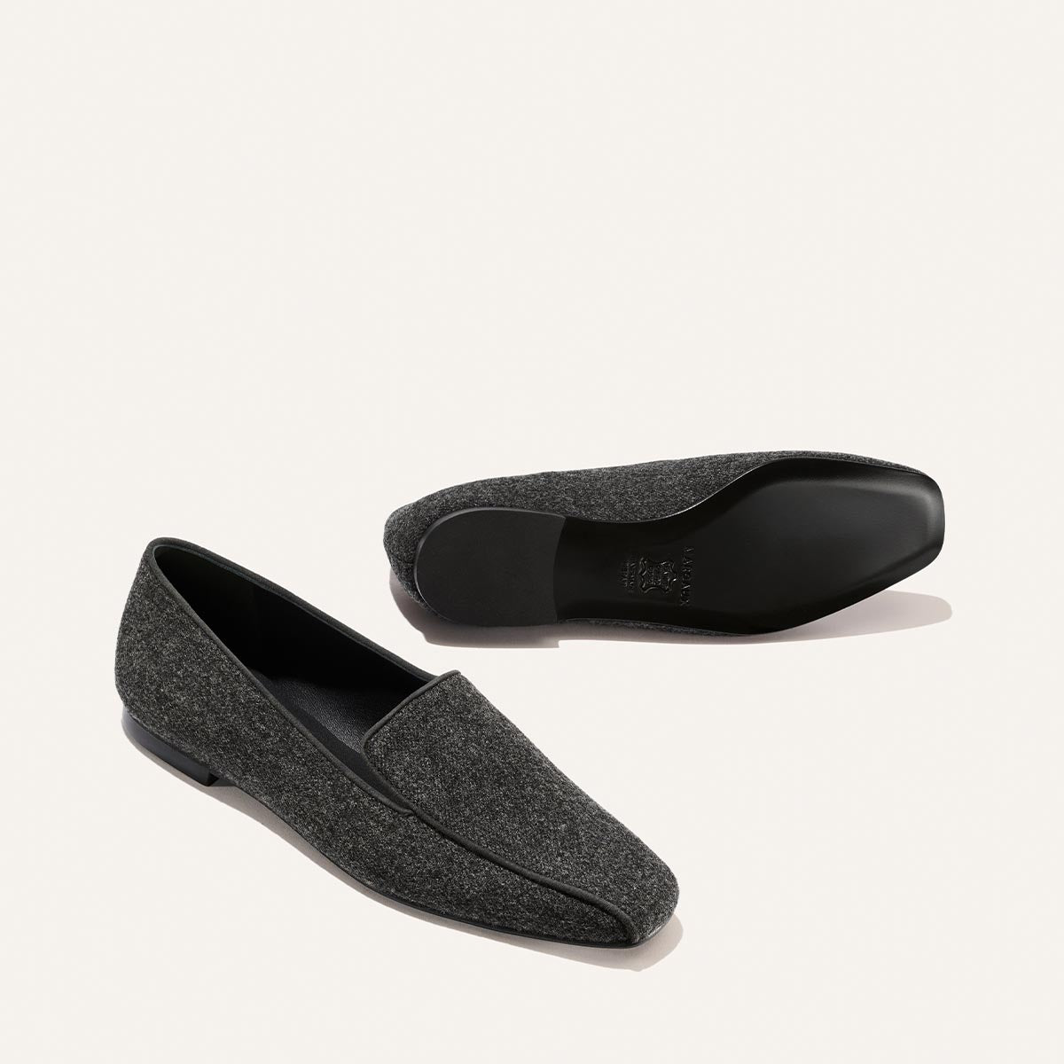 Two grey flannel The Portia Loafer shoes, one shown from the side and one from the bottom showing the sole.