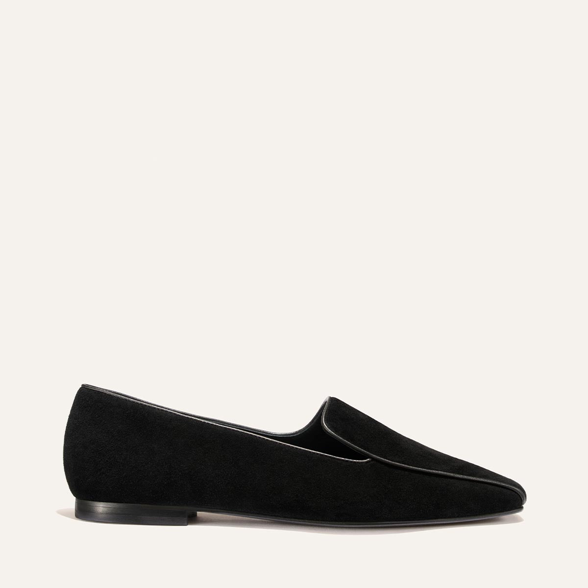 The Portia Loafer by Margaux in black suede, featuring a low heel and a slightly pointed toe, is shown from the side against a plain light background.