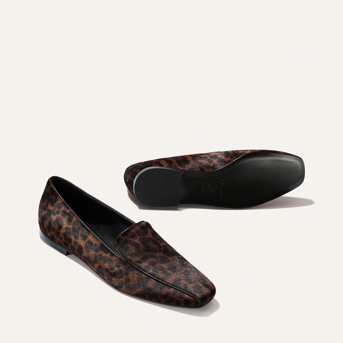 A pair of The Portia Loafer - Chocolate Leopard Haircalf brown leopard-print loafers with a flat heel, one shown from the side and one shown from the sole.