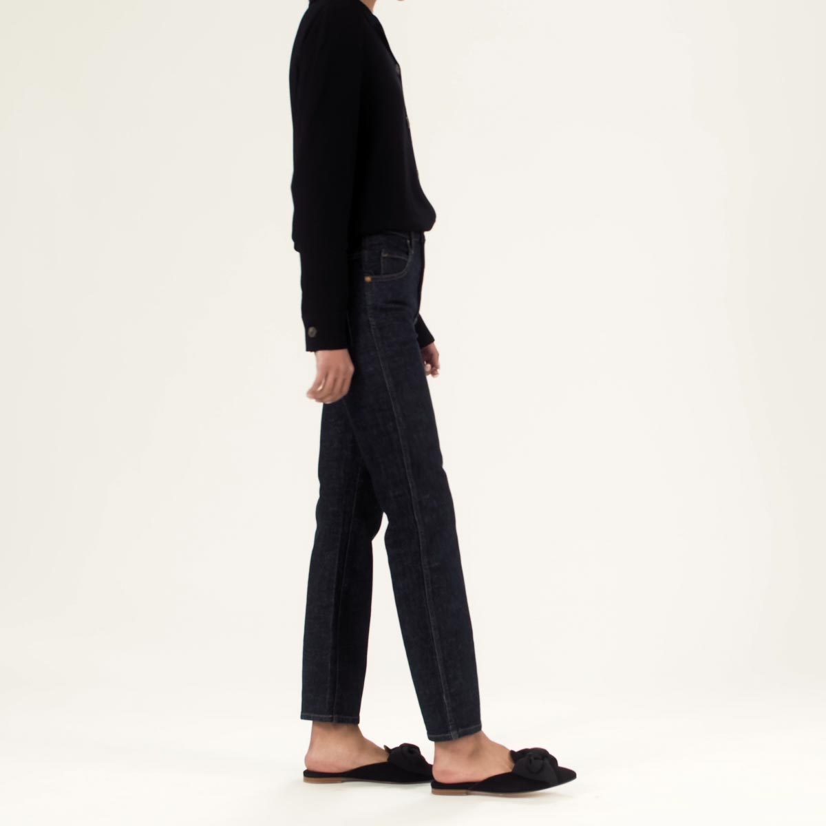 The Mule in Black Suede shown on model styled with black denim and a black knit cardigan.
