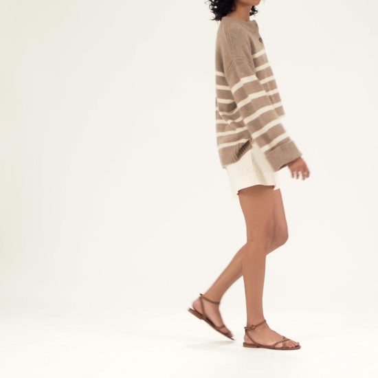 The Flat Sandal in Saddle Nappa shown on model styled with white poplin shorts and a beige and white striped sweater.