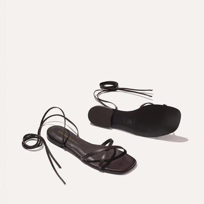 The Wrap Sandal in Espresso Nappa by Margaux features strappy wrap details, square toes, and long ankle laces—one displayed top-up, the other sole-out—offering iconic getaway style and versatile summer wear.