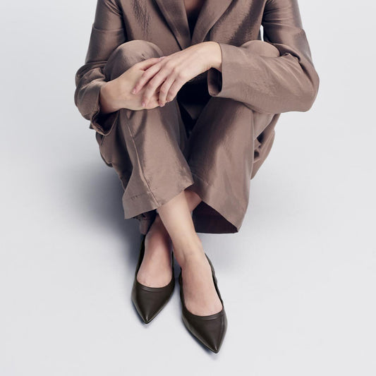 A person sitting on the floor wearing a brown suit and dark espresso pointed-toe The Roma - Espresso Nappa ballet flats.
