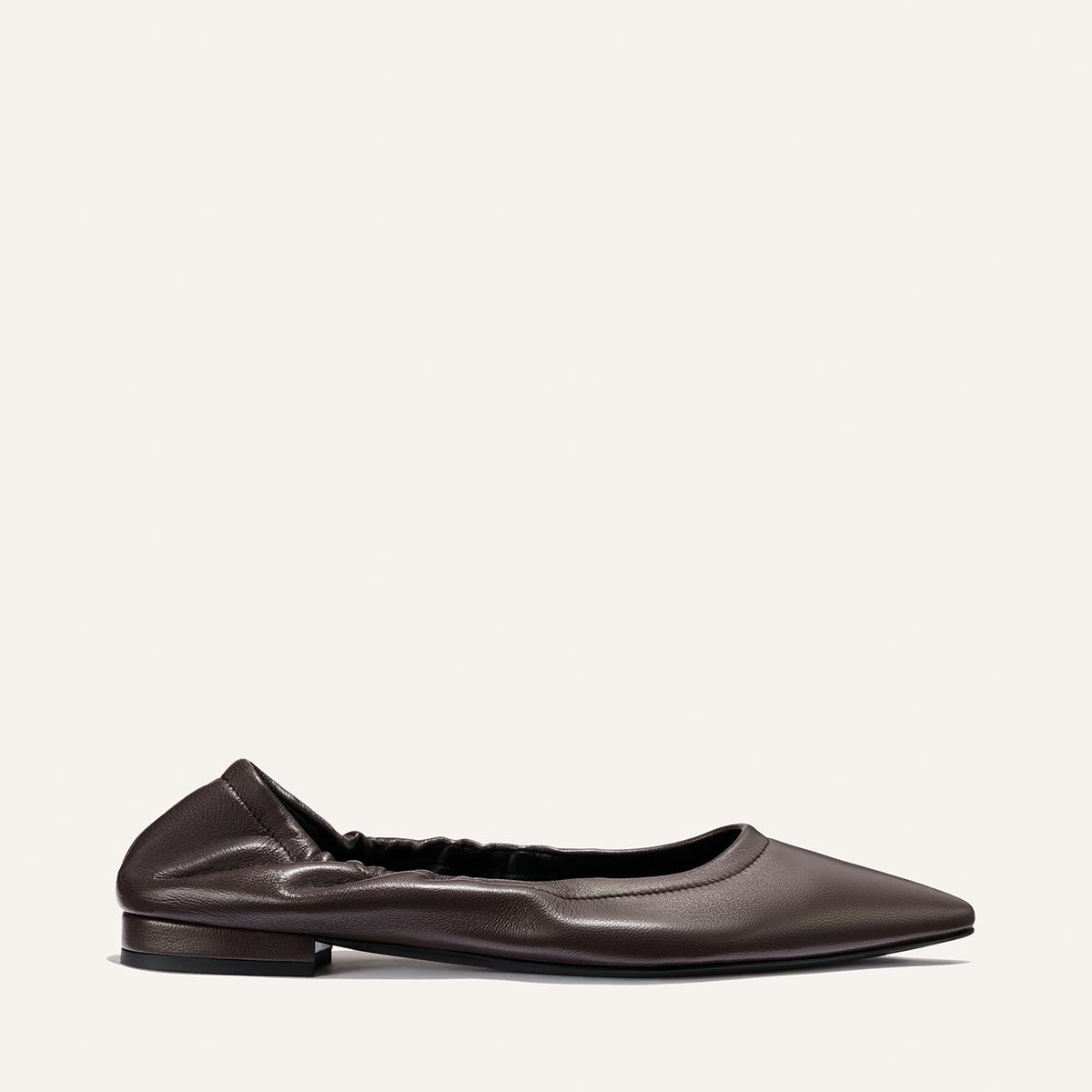 A single elegant ballet flat, The Roma in Espresso Nappa by Margaux, crafted from smooth brown leather with a pointed toe, slight heel, and an elasticized back, is shown in profile against a plain white background.