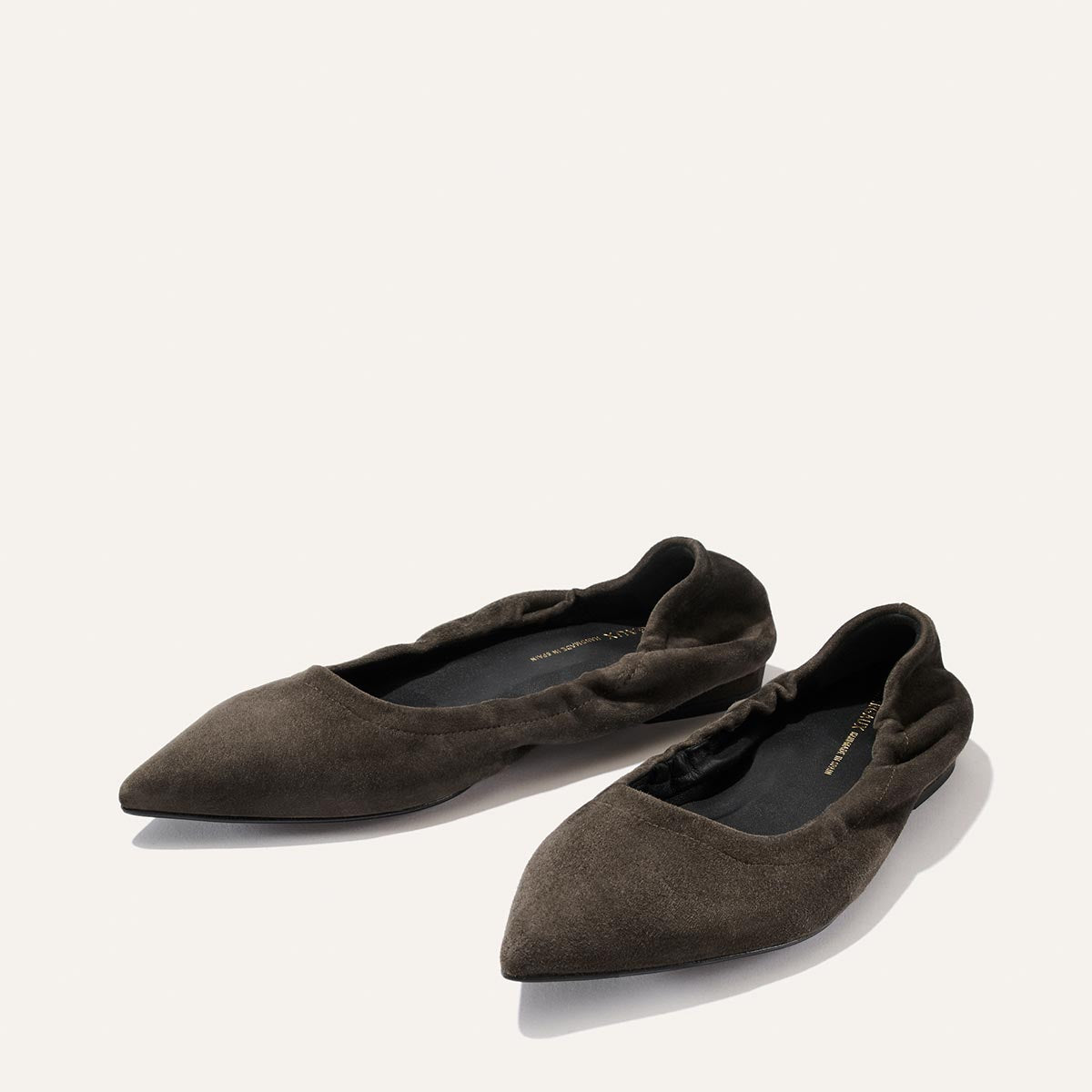 A pair of Margaux’s “The Roma” ballet flats in graphite suede, featuring pointed toes and elasticized heels for a comfortable fit, displayed on a plain light background.