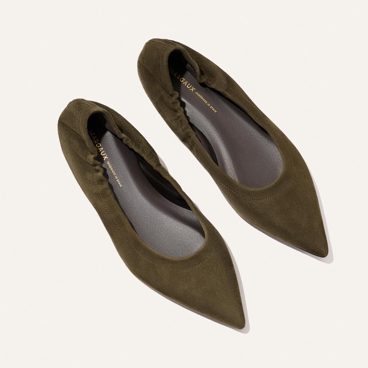The Roma - Moss Suede flats by Margaux, crafted from olive green suede with a pointed toe, are displayed from above on a plain light background.